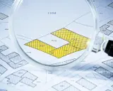 Lupa sobre plano catastral, resaltando parcelas amarillas con números. Detalle para calcular el valor catastral de una vivienda.