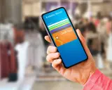 Mano sostiene un teléfono con una aplicación de wallet digital que muestra tarjetas de crédito.