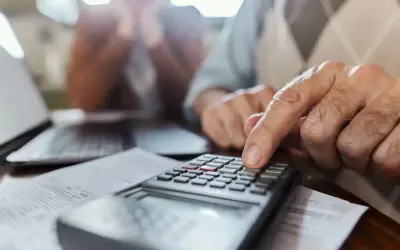 Un hombre mayor calcula con una calculadora, ayudando a alguien a saber mi base reguladora.