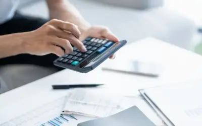 Persona calculando la declaración de la renta con calculadora y documentos.