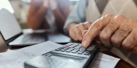 Un hombre mayor calcula con una calculadora, ayudando a alguien a saber mi base reguladora.