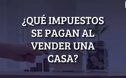 ¿Qué impuestos se pagan al vender una casa? Mano colocando monedas en una alcancía con una planta, junto a una casa de juguete y pilas de monedas.