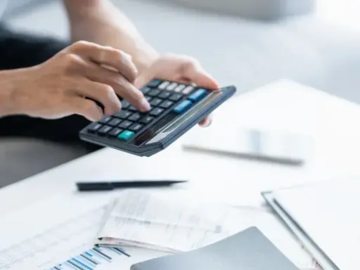 Persona calculando la declaración de la renta con calculadora y documentos.