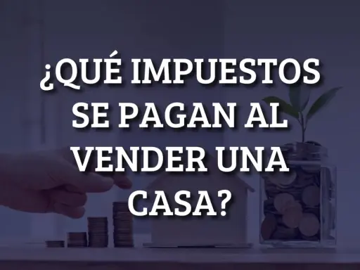 ¿Qué impuestos se pagan al vender una casa? Mano colocando monedas en una alcancía con una planta, junto a una casa de juguete y pilas de monedas.