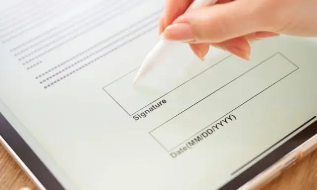 Mano firmando un contrato de arrendamiento digitalmente en una tableta con un lápiz óptico.
