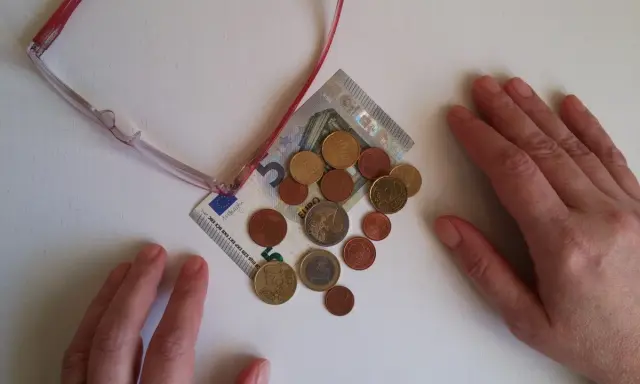 Manos sobre billetes y monedas, sugiriendo aportaciones a planes de pensiones IRPF.