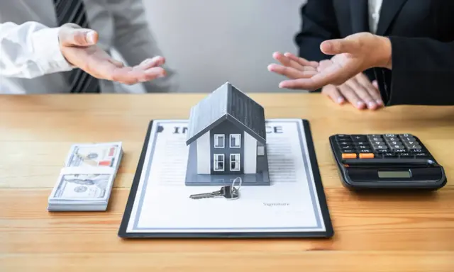 Negociación de honorarios inmobiliaria: casa modelo, llave, dinero y calculadora sobre un contrato.