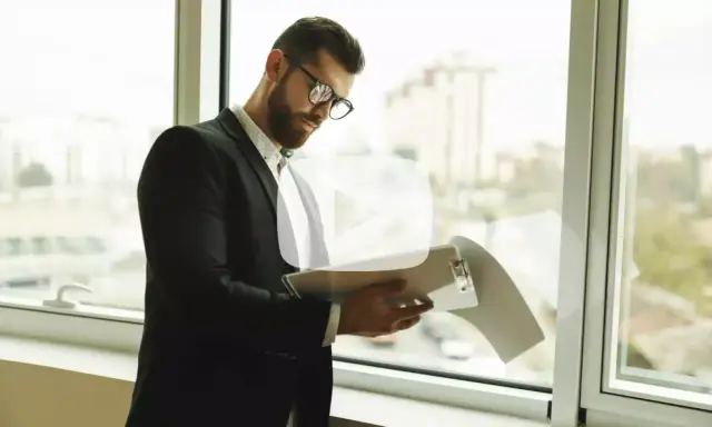 Hombre con gafas revisa documentos. Explica qué es un aval bancario para alquiler, una garantía para el arrendador.