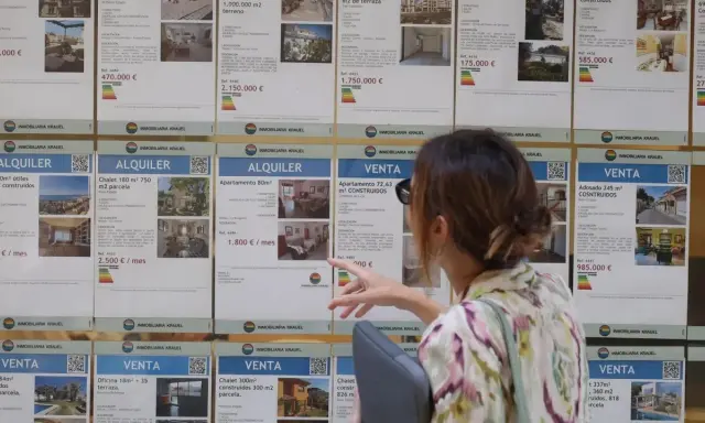 Mujer señalando anuncios de alquiler y venta de inmuebles, buscando opciones para el bono joven alquiler.