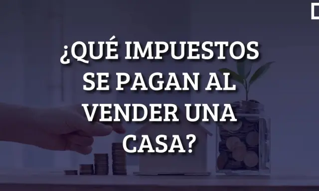 ¿Qué impuestos se pagan al vender una casa? Mano colocando monedas en una alcancía con una planta, junto a una casa de juguete y pilas de monedas.